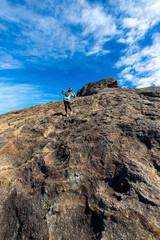 brave backpacker girl descends from frenchman peak in cape le grand national park in western australia, hiking and climbing a mountain with a backpack