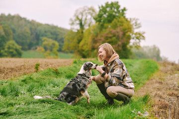 Outdoor portrait of beautiful young woman playing with australian shepherd dog - 539460029