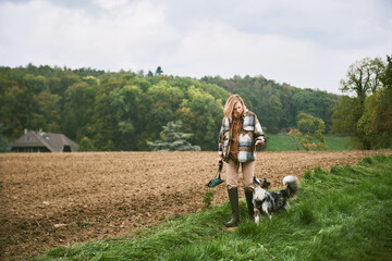 Outdoor portrait of beautiful young woman walking with australian shepherd dog