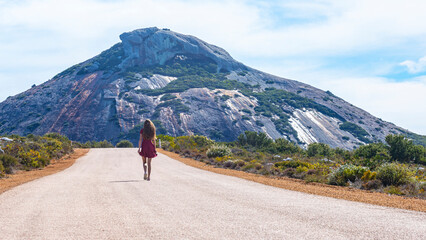 long-haired girl in a dress walks along a road in the middle of nowhere in western australia...
