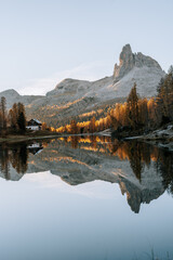Erste Sonnenstrahlen am Lake Fedare / Lago di Federa in den Belluner Dolomiten zum Sonnenaufgang. Es ist Herbst und der Wald am See leuchtet gelb. Sonnenaufgang Dolomiten 2