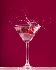 Raspberry splash in a martini cocktail glass on red background