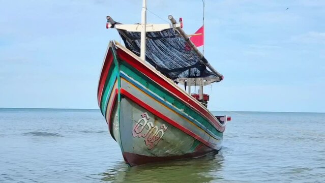 Songkhla - Thailand. September 24, 2022 : 'Koleh boat' is used as fishing boats by the local fishermen of southern Thailand. parked on the beach The backdrop is the bright blue sky and sea.