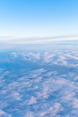 Fototapeta na wymiar Background of a blue heavenly sky with fluffy dense clouds, top view from an airplane, vertical frame. Sky Gradient. Can be used as advertising background, overlay. Travel concept.