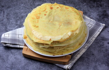 A stack of round thin pancakes on a wooden kitchen board