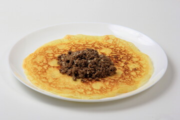Minced meat filling on a large thin pancake. Making a pancake filled with meat or heart