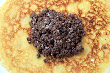 Minced meat filling on a large thin pancake. Making a pancake filled with meat or heart
