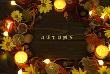 dark rustic wooden background with candles, autumn leaves and words 