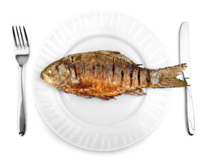 Fried fish on white plate with fork and knife, closeup