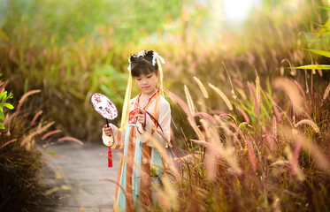 Portrait photo of beautiful Asian girl in Chinese fountain grass field on sunset