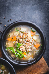 Mushrooms transparent  soup with champignon, vegetables and pearl barley. Simple and hearty cuisine for the cold season. Forest food, vegan proteins. Baltic cuisine
