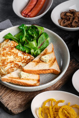 Omelet with spinach and toast on a plate. Scrambled eggs for breakfast close-up