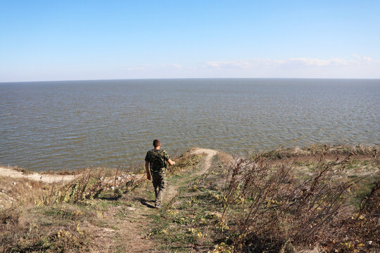 man walking towards a cliff over the lake