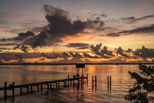 Scenic view of a pier at the sea during the sunset with moody clodus