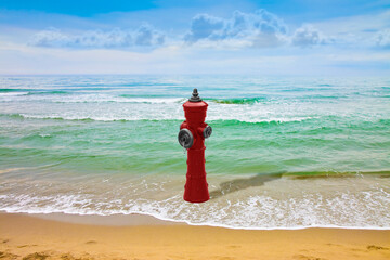 An improbable hydrant at the seaside - Plenty of water illogical concept image - obrazy, fototapety, plakaty