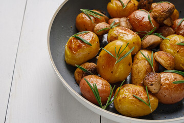 Baby potatoes fried with champignons, spices and rosemary