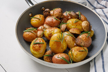 Baby potatoes fried with champignons, spices and rosemary