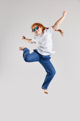 Have a fun. Happy little girl, kid in white t-shirt and jeans jumping high isolated over white...