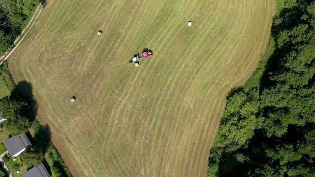 Aerial Birds Eye View Of Tractor Pulling Trailed Across Green Field In Chmielno