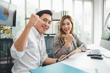 Excited young Asian startup business team celebrate successful and victory and hand up at office and looking at camera, happy euphoric proud Asian male and female professional winner feel overjoyed