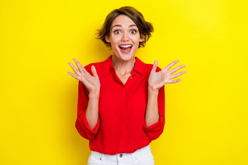 Photo of astonished positive girl open mouth raise arms palms isolated on yellow color background