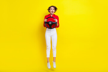 Fototapeta na wymiar Full body photo of impressed speechless lady arms hold wheel jump isolated on yellow color background