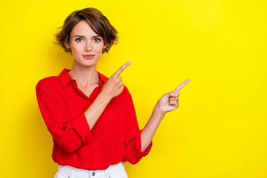 Portrait of nice pretty sweet girl with bob hairdo dressed red shirt fingers indicating empty space isolated on yellow color background