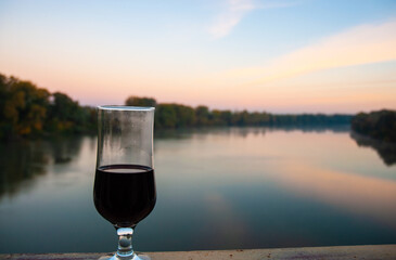 A glass of red wine on the bridge over the river