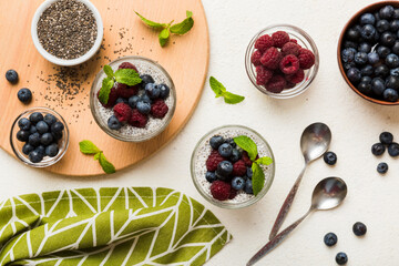 Healthy breakfast or morning with chia seeds vanilla pudding raspberry and blueberry berries on table background, vegetarian food, diet and health concept. Chia pudding with raspberry and blueberry