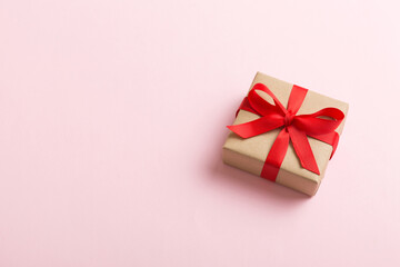 Wrapped christmas or other holiday handmade present in craft paper with colored ribbon. Present box, decoration of gift on table, top view with copy space