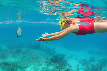 Happy family - active girl in snorkeling mask dive underwater, see tropical fishes in coral reef...