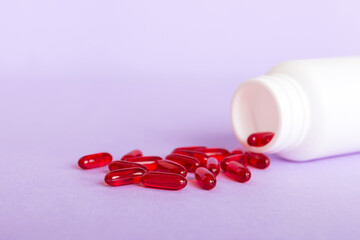 Red pills spilled around a pill bottle. Medicines and prescription pills flat lay background. Red medical capsules