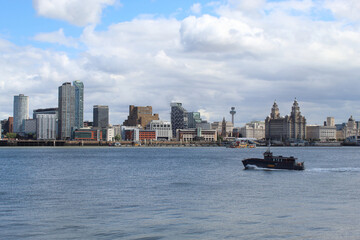 A beautiful image of the famous Liverpool Skyline and cityscape with the River Mersey in front. A speed boat and the ferry can be seen on the River.