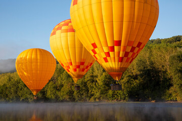 hot air balloons fly low over dordogne river in southern france - obrazy, fototapety, plakaty