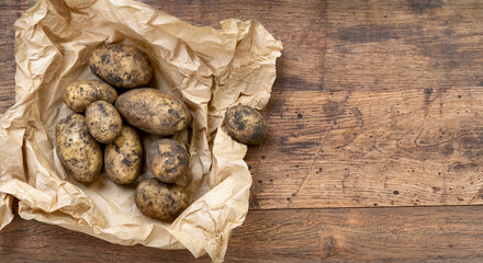 Potatoes in paper packaging on old wooden table