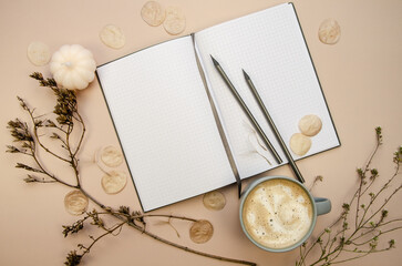 Notepad copyspace, gray pencils and cup of latte  on tan begie background  with dry brown branches. Autumn minimal flatlay blank pages  template muckup 
