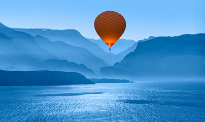 Blue mountain landscape with fog and pine forest at sunset - 
Hot air balloon fly over blue...