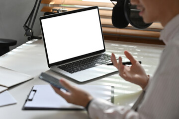 Close up with Radio host or blogger using laptop recording audio podcast in home studio.