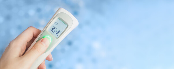 Female hand holding a modern infrared thermometer