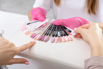 Professional manicurist showing colorful nail polish to check the finish result.