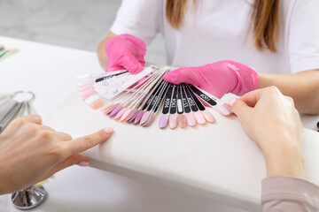 Professional manicurist showing colorful nail polish to check the finish result.