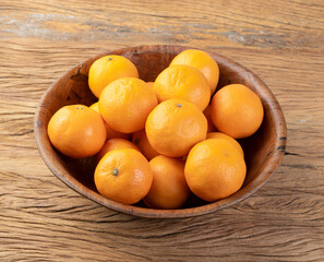 Mini tangerines in a bowl over wooden table