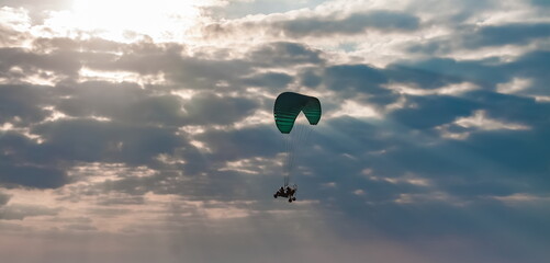 Paraglider on the background of a sunset sky with clouds in summer