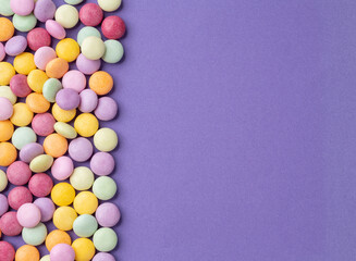 Colorful candies over purple background with copy space