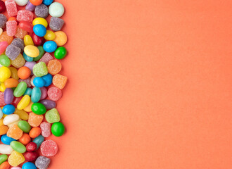 Obraz premium Colorful candies over orange background with copy space