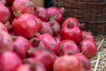Harvest of ripe pomegranate on dry straw at outdoor farmers market in Tbilisi Georgia. Vegetarian healthy food