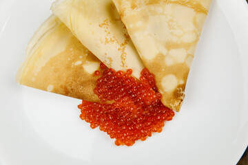 delicious pancakes with red caviar on a plate.
