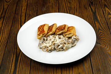 delicious pancakes with fried mushrooms on a plate.
