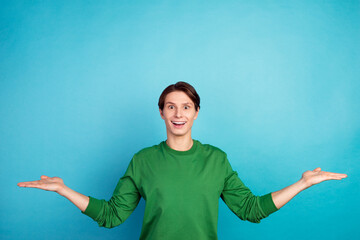 Portrait of cheerful guy holding palms copy blank place space weighing isolated over blue color background