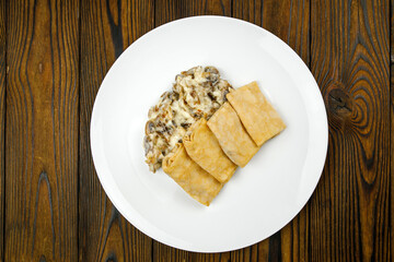 delicious pancakes with fried mushrooms on a plate.

